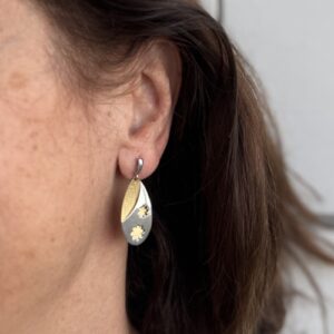 Foto gioiello indossata: orecchini pendenti due ori (oro bianco e oro giallo) con fiore e lavorazione