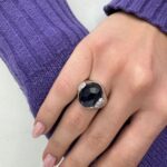 Foto gioiello indossata: anello oro bianco con pietre preziosa centrale iolite e diamanti laterali