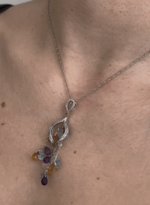 Foto gioiello indossata: collana in oro bianco con ciondolo pendente con diamanti e pietre preziose