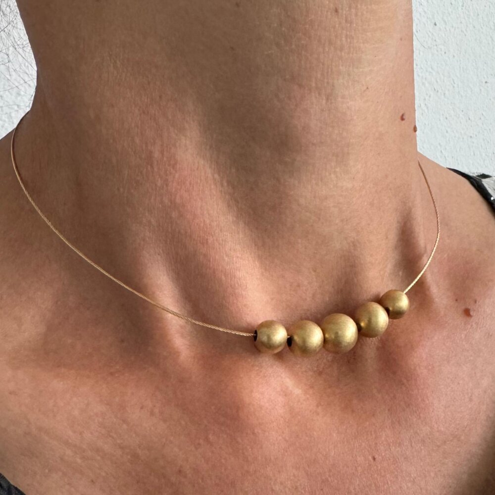 Foto gioiello indossata: collana girocollo in oro giallo con cinque sfere dorate