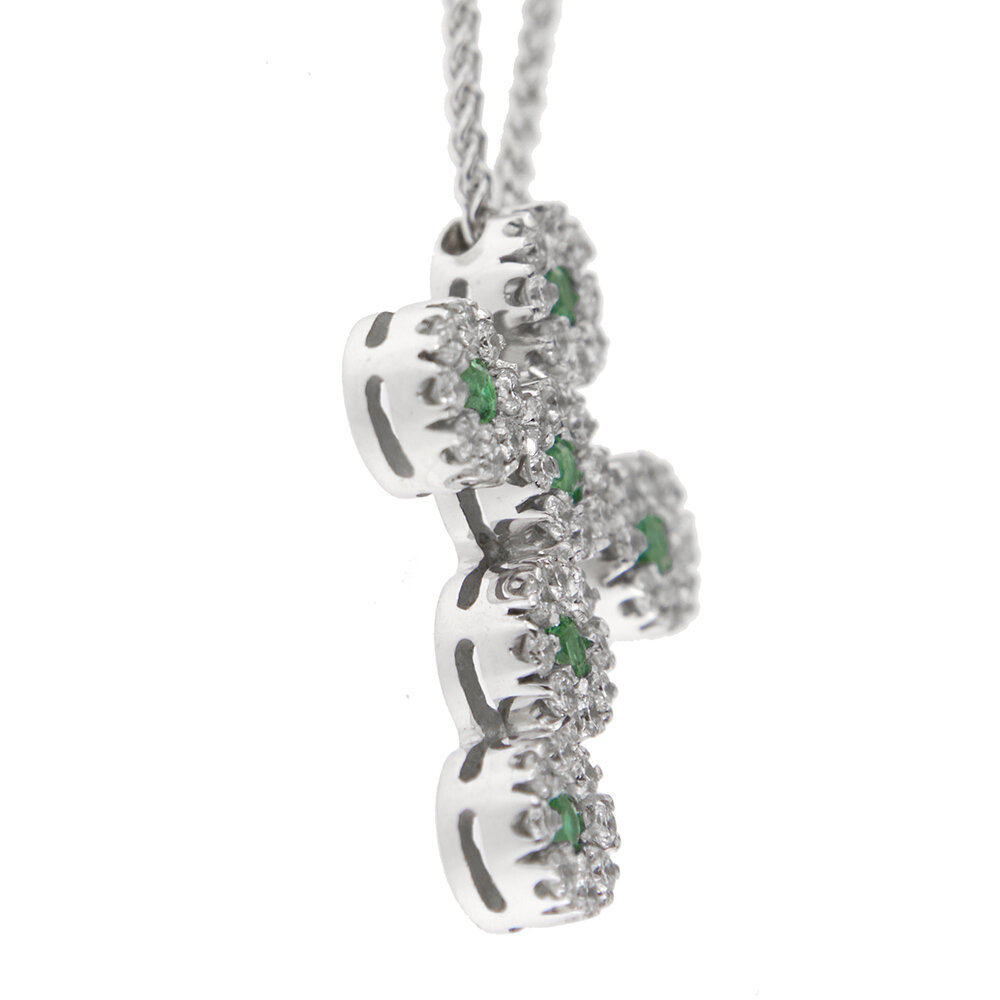 Dettaglio ciondolo profilo croce con diamanti e smeraldi su collana oro bianco