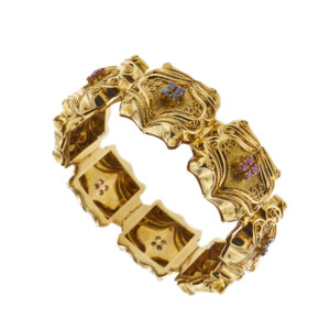 Bracciale tank a fascia in oro giallo 18 kt con lavorazione in filigrana composta da 8 elementi con al centro alternati 4 zaffiri e 4 rubini da 0.05 ct cad, totale 1,60 ct, chiusura a cassetta con sicure, modello brevettato.