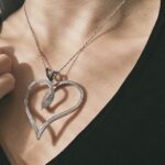 Foto gioiello indossata: ciondolo a forma di cuore in oro bianco con diamanti trasparenti e neri