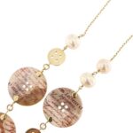 dettaglio bottoni e perle su collana in oro giallo
