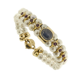 Bracciale doppio filo semirigido di perle d’acqua dolce da 6-6.5 mm in oro giallo 18kt, colore bianco, sfumature grigia con zaffiro ovale taglio cabochon da 2 ct e 8 rubini rotondi taglio cabochon da  0.10 ct cad. su base oro come chiusura.