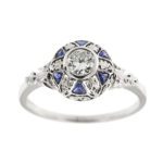 Anello Art Deco in oro bianco 18kt con diamante taglio vecchio europeo da 0.25 ct - colore FG e purezza VS e intorno 6 zaffiri triangolari da 0.05 ct cad. e lavorazione traforata e floreale.