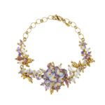 Bracciale con fiore centrale smaltato a mano con la tecnica dello smalto a fuoco in oro giallo 18kt ; impreziosito da due stelle in bianco con diamanti, taglio brillante da 0.01 ct cad. Contornato da pendenti in oro, perle e pietre colorata (tormalina, acquamarina, ametiste e quarzi). Brand: Gabriella Rivalta, made in Italy.
