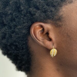 Foto gioiello indossata: orecchini a monachella rotondi in oro giallo con due fili di diamanti