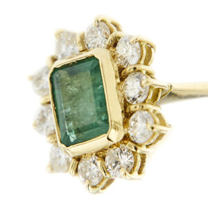 zoom dettaglio smeraldo e diamanti su anello halo in oro giallo