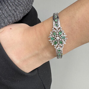 Foto gioiello indossata: bracciale semirigido in oro bianco vintage con fiore con smeraldi e diamanti