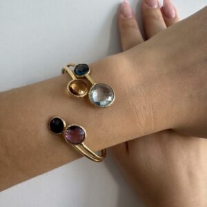 Foto gioiello indossata: bracciale rigido bangle in oro giallo con pietre colorate (topazio, quarzo citrino, ametista e granato)