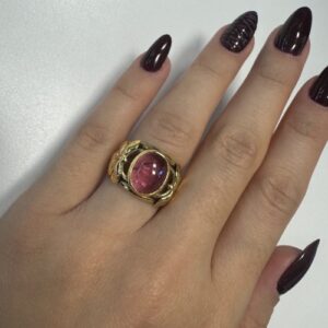 Foto gioiello indossata: anello a fascia in oro giallo con tormalina rosa ovale centrale e lavorazione a foglie