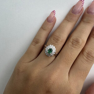 Foto gioiello indossata: anello in oro bianco a fiore con smeraldo e due diamanti